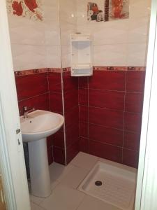 une petite salle de bains avec lavabo et carrelage rouge dans l'établissement Residence Bassatine, à Temara