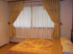 a bedroom with a bed and a window with curtains at Prestige Vacation Apartments - Hanbi Mansions in Baguio