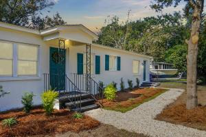 a white house with a blue door and a yard at Chic Charleston Home - Half Mile to Park Circle! in Charleston