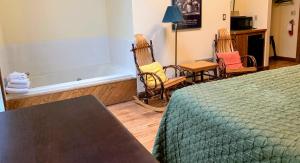 a room with a bed and two chairs and a bath tub at Gordon Beach Inn in Union Pier