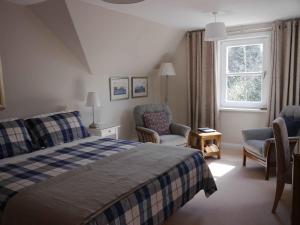 a bedroom with a bed and two chairs and a window at Balmillig B&B in Helensburgh