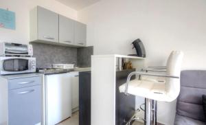 a kitchen with white cabinets and a microwave and a chair at Gite Casa di Emma in Santo-Pietro-di-Tenda