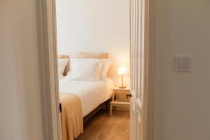 a bedroom with a bed with white sheets and a lamp at Caparica Downtown Apartment in Costa da Caparica