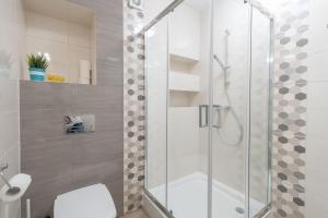a bathroom with a glass shower with a toilet at Plażowe Apartamenty Grzybowo in Grzybowo +25 photos
