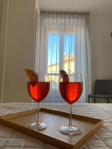 dos copas de vino en una bandeja de madera en una cama en Affittacamere Le Grotte - Le Grotte Rooms & Apartments en Camerano