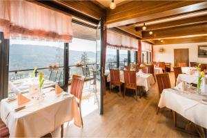 un restaurante con mesas y sillas blancas y ventanas en Waldhotel Sonnenberg, en Bollendorf