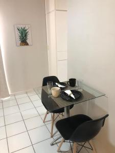 einem Glastisch mit 2 Stühlen und einem Tisch mit einer Platte in der Unterkunft Flat no Executive Arrey Hotel in Teresina