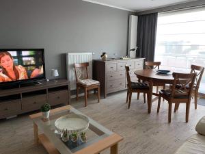 a living room with a television and a table and chairs at Gelijkvloers zeezicht appartement Sterckx in Blankenberge