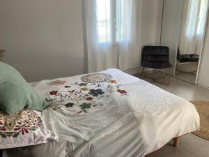 Una cama con un edredón blanco con flores. en Sitio Nathalie et Jos, en Saint-Laurent-de-Carnols 15 fotos más