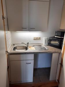una pequeña cocina con fregadero y microondas en Easy Stay Rooms, en Stuttgart