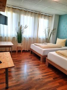 two beds in a room with wooden floors and curtains at Easy Stay Rooms in Stuttgart