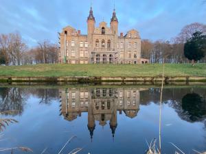 een oud kasteel met zijn reflectie in het water bij Hotel Am Schlosspark in Mallin