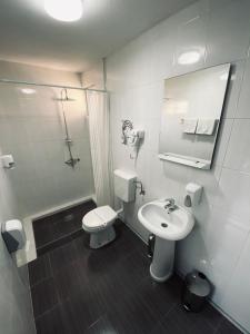 a white bathroom with a toilet and a sink at Hotel Djerdan in Kraljevo