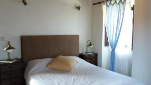 um quarto com uma cama branca e uma janela em Pátio das Mós em Vila Nova de Poiares