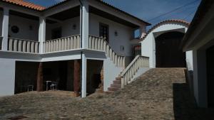 a white house with a balcony and stairs at Pátio das Mós in Vila Nova de Poiares