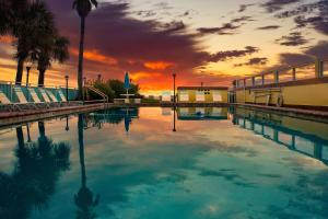 a large swimming pool with a sunset in the background at Sea Shells Beach Club in Daytona Beach