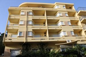 ein gelbes Gebäude mit Balkon an der Seite in der Unterkunft Hôtel Alexandra in Roquebrune-Cap-Martin