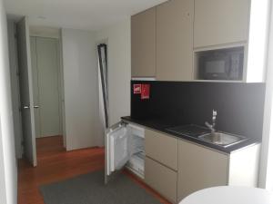 eine kleine Küche mit Spüle und Mikrowelle in der Unterkunft Maia Centro in Maia