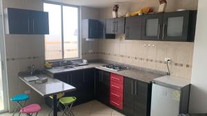 a kitchen with black cabinets and pink and green stools at Espectacular suite en malecón de Atacames in Atacames