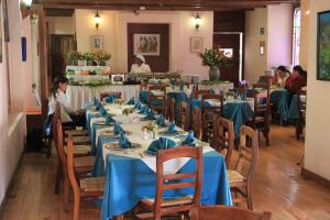 a dining room with blue tables and chairs and people at Hotel Casa Mexicana in San Cristóbal de Las Casas