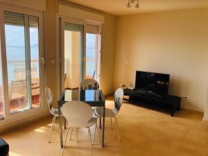 een eetkamer met een tafel en stoelen en een televisie bij Punta Cormoran in La Manga del Mar Menor