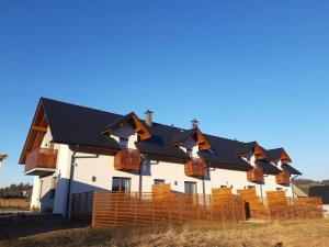 a building with black roofs and orange chairs at Apartament Przy Potoku in Zubrzyca Górna