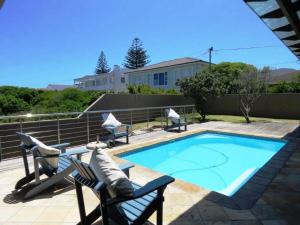 a small swimming pool with two chairs and a table at Whalesong Villa in Hermanus