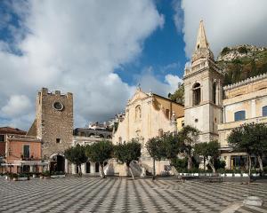 a large building with a clock on the side of it at San Domenico Palace, Taormina, A Four Seasons Hotel in Taormina
