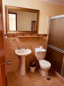ein Badezimmer mit einem Waschbecken, einem WC und einem Spiegel in der Unterkunft Hotel Sevilla in Ayacucho