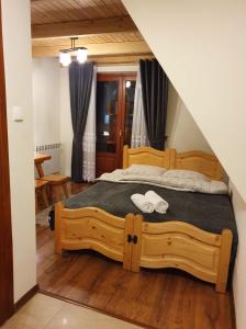 a bedroom with a wooden bed with two towels on it at Willa U Kantora in Murzasichle
