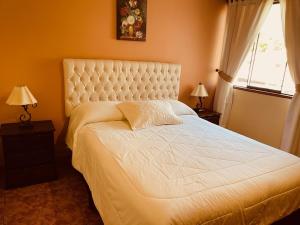 um quarto com uma grande cama branca e 2 candeeiros em Hotel Sevilla em Ayacucho