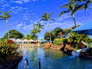 una piscina in un resort con palme di ALOHA - Poipu Beach Vacation Condo a Koloa