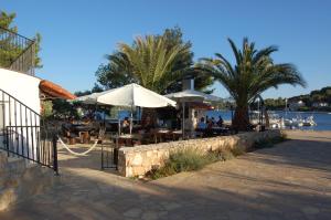 ein Restaurant mit Tischen und Sonnenschirmen neben dem Wasser in der Unterkunft Gorgonia Apartments in Verunić