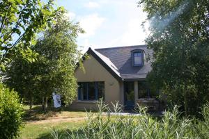 Casa amarilla con ventana y árboles en Camping les vergers de Squividan ***, en Tréffiagat