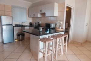 a kitchen with a counter and two bar stools at 516 Umdloti Resort in Umdloti