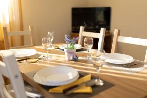 a wooden table with plates and wine glasses on it at Apartman Doris in Milohnići