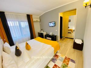 a bedroom with a bed with a yellow and white bedspread at Pensiunea Camena in Piatra Neamţ +49 photos