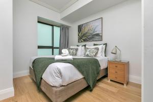 a bedroom with a large bed with a green blanket at Ultimate outdoor-living Urban Getaway! 1 Carpark in Auckland