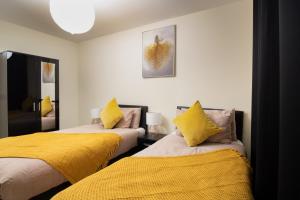 1 dormitorio con 2 camas con almohadas amarillas en Virexxa Bletchley - Executive Suite - 2Bed Flat with Free Parking en Milton Keynes