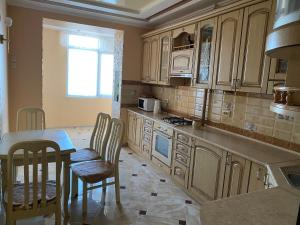 a kitchen with wooden cabinets and a table and chairs at Luxury apartment 2 in Truskavets