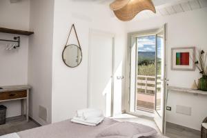 a white bedroom with a mirror and a window at Oliveto Bed and Breakfast in Alghero