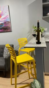 a table with two yellow chairs and a bottle of wine at Nomada Republic Hotel Panama City in Panama City