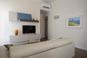 uma sala de estar branca com um sofá branco e uma televisão em La Casa di Nausicaa : il piacere dell'ospitalità em Reggio di Calabria