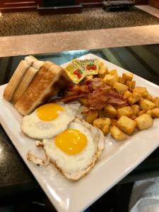 talerz jedzenia śniadaniowego z jajkami, bekonem i ziemniakami w obiekcie Days Inn by Wyndham Sudbury & Conference Centre w mieście Sudbury