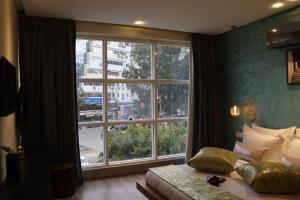 Luxury Appartement Noor في فاس: غرفة نوم مع نافذة كبيرة وسرير واريكة