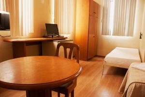 a small room with a table and a desk with a laptop at Hara Palace Hotel in Curitiba