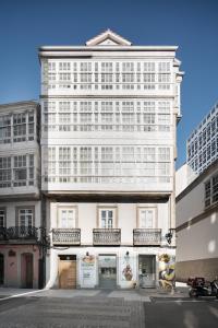 ein hohes weißes Gebäude mit Fenstern und Balkonen in der Unterkunft Atico en Santa Catalina in A Coruña