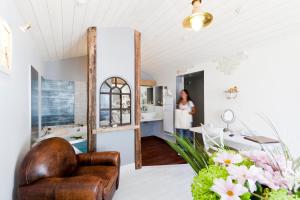 a woman standing in a bathroom with a mirror at Hôtel Restaurant & Spa Plaisir in Le Bois-Plage-en-Ré