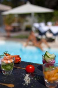 a table with two glasses of vegetables and a tomato at Hôtel Restaurant & Spa Plaisir in Le Bois-Plage-en-Ré