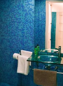 a blue tiled bathroom with a sink and a mirror at 7Rios Rooms in Lisbon